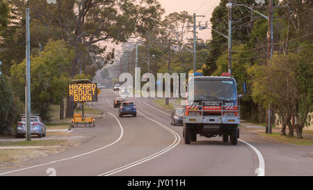 A variable message sign warning motorists of smoke over the road and a fire engine during a hazard reduction burn in Sydney Stock Photo