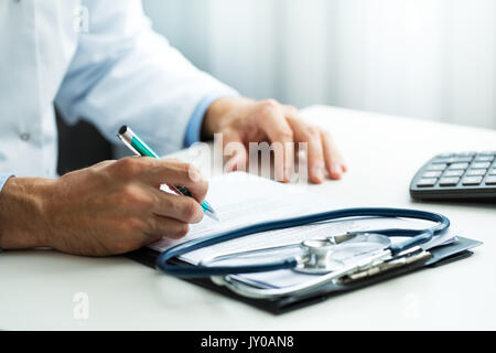 doctor writing prescription at desk in clinics office Stock Photo