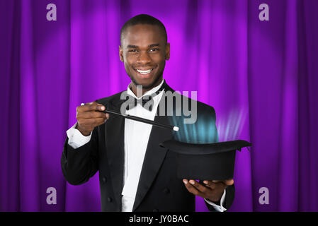Young Happy Magician Showing Magic With Magic Wand And Hat Stock Photo