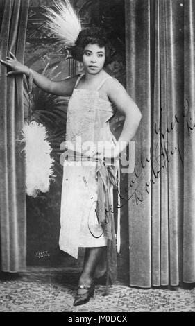 Portrait of an African American woman standing and leaning with her right  arm on a curtain