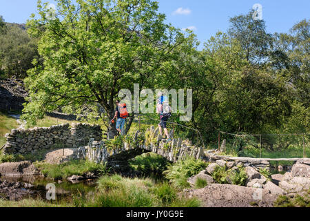 Two men carrying children over Slater's Bridge Little Langdale, Lake District, Cumbria Stock Photo