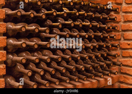 Winy bottles lie on bricks in basement, old wine cellars with bottles and barrels Stock Photo