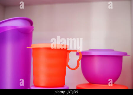 Colorful plastic tableware bowl and jug on shelf Stock Photo