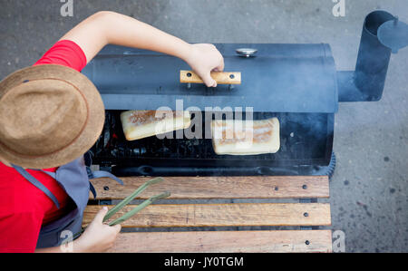 The chef in the hat bakes a Panini in the oven on the coals Stock Photo