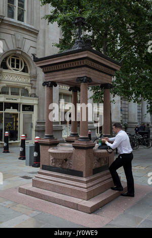 A businessman checks messages on his mobile phone in Cornhill, City of London, on 11th August, 2017, in London, England. Stock Photo
