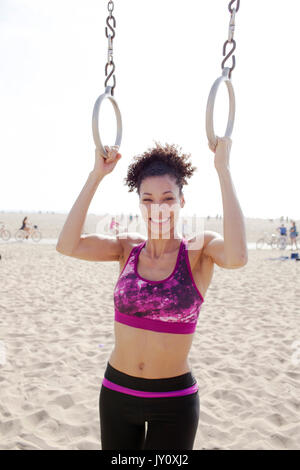 Fit woman doing pull ups with gymnastic rings at the gym or at