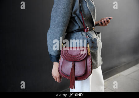 Mid section of woman in grey jacket with red leather handbag Stock Photo