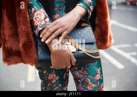 Woman in silk suit with black handbag, close up mid section Stock Photo