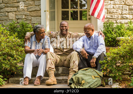 Soldier sitting on front stoop with parents Stock Photo