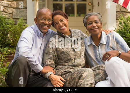 Portrait of soldier sitting on front stoop with parents Stock Photo