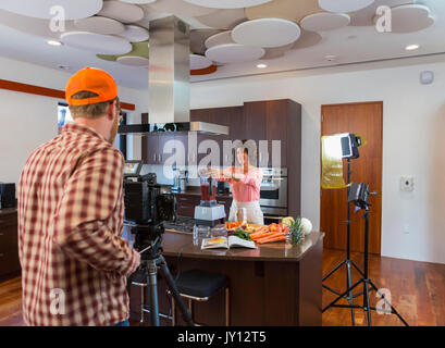Cameraman recording woman preparing smoothie in domestic kitchen Stock Photo