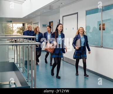 Group of students are walking down the school corridor together wearing uniform. Stock Photo