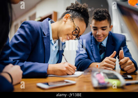 Teen students are working together and taking notes in lesson time at school. Stock Photo
