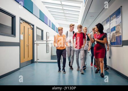 Teacher and students walking down hallway Stock Photo - Alamy