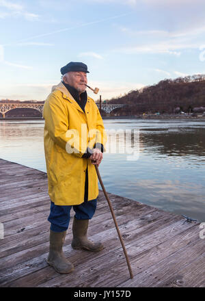 Older Caucasian fisherman standing on dock Stock Photo