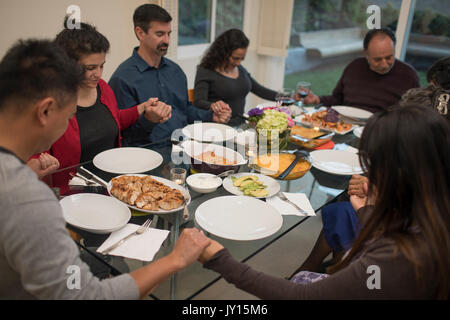 Multi-generation family praying before eating meal Stock Photo