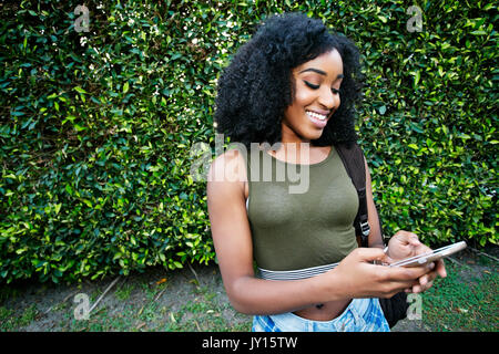 Black woman texting on cell phone outdoors Stock Photo