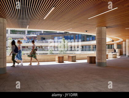 Three women walk across the elevated covered galleries of the circle. Broadgate Circle, London, United Kingdom. Architect: Arup Associates, 2016. Stock Photo
