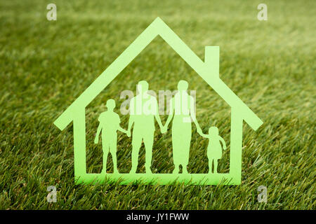 Close-up Of Papercut Of Family House On Grassy Field Stock Photo