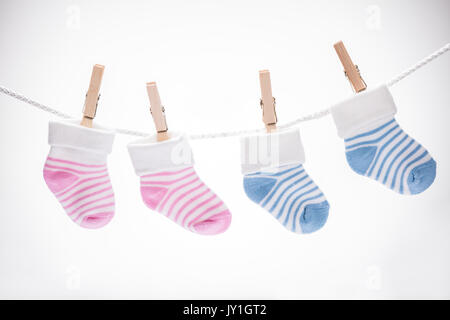 Two Pairs Of Baby Sock Hanging On Rope Using Wooden Clip Against White Background Stock Photo