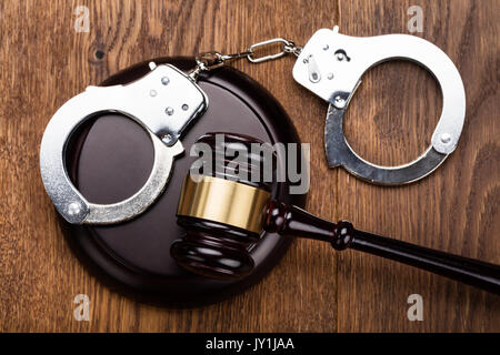 High Angle View Of Judge Gavel And Handcuffs On Wooden Desk Stock Photo