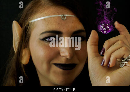 A young female dressed as an elf with a polyhedral twenty sided die often used in role playing games. Stock Photo