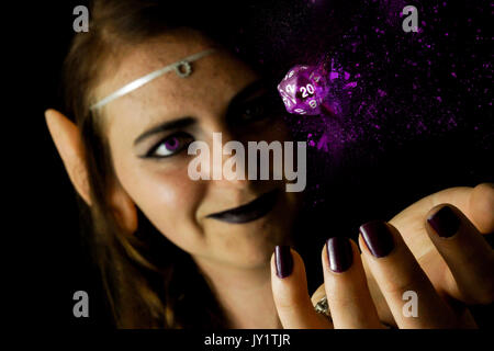 A young female dressed as an elf with a polyhedral twenty sided die often used in role playing games. Stock Photo