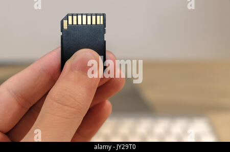SD memory card in front of a desktop computer and keyboard Stock Photo