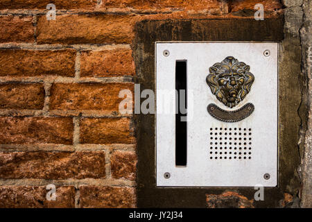 brass doorplate and doorbell in a shape of a lion's head on an old, cracked brick wall , Venice, Italy Stock Photo