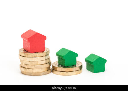 Housing market. British pound coins isolated on white background with red and green wood toy houses. Symbols of borrowing, loans, debt and mortgages Stock Photo