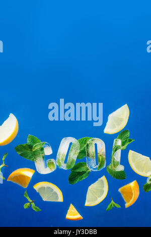 Ice cube lettering with frozen mint leaves, lemon slices and oranges on a blue background . Text says Cool. Stock Photo
