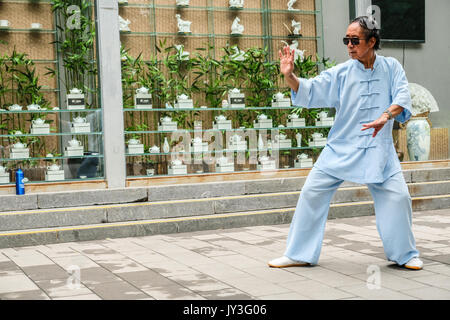 A Chinese man in traditional Chinese dressing practicing Tai Ji at Yu Yuan Tan park in Beijing, China Stock Photo