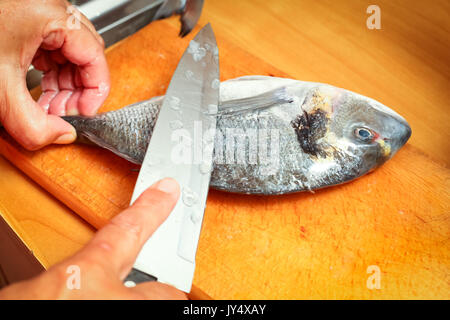 Detail of preparing bream fish on chopping board. Stock Photo