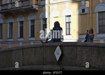 Woman posing for mobile phone photo on bridge balustrade Stock Photo