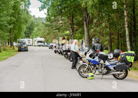 Byglandsfjord, Norway - August 1, 2017: Travel documentary of rest area in forest landscape with motorcycles and caravans. Two bikers talking. Stock Photo