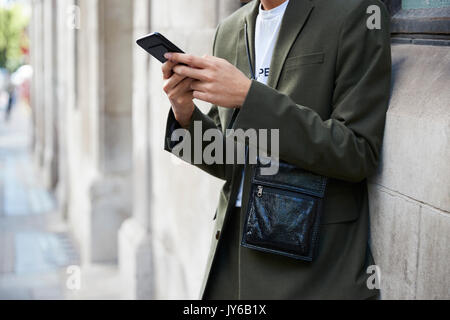 Man in dark green suit using smartphone, mid section Stock Photo