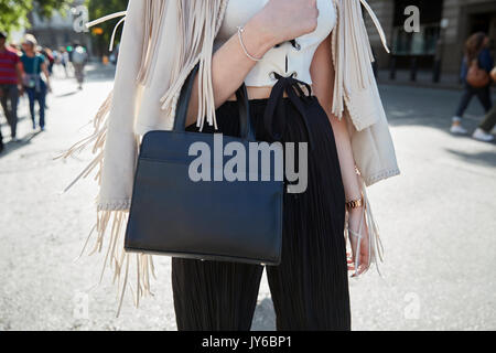 Woman in a fringed cream jacket and black leather bag Stock Photo