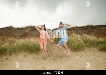 Couple on the beach having fun and jumping Stock Photo