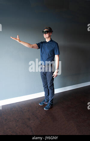 Young engineer in holographic headset creating a virtual surrounding using special gestures - gaze Stock Photo