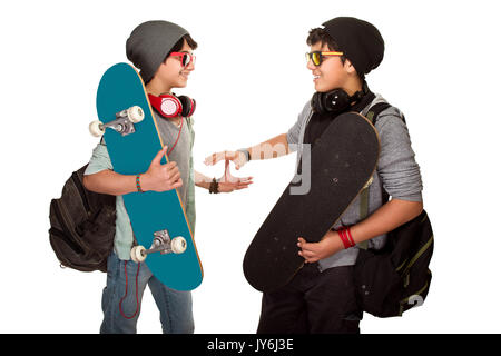 Two happy skateboarders acclaiming each other isolated on white background, best friends wearing stylish hats, sunglasses and listening music from ear Stock Photo
