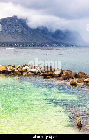 Amazing peaceful view on the Betty's Bay, beautiful blue-green lagoon with clear water, mountains in the fog near shore, Atlantic Ocean, South Africa Stock Photo