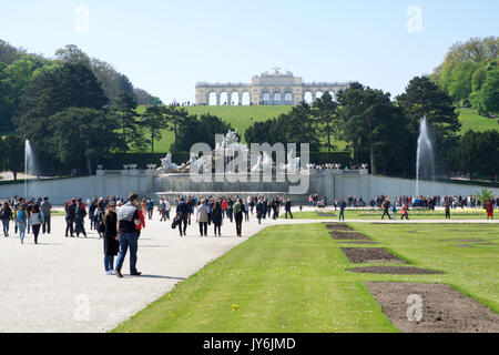 VIENNA, AUSTRIA - APR 30th, 2017: Neptune Fountain Neptunbrunnen in great parterre of Schoenbrunn public park with flowers in the foreground and Gloriette in the back, Schoenbrunn palace - former imperial summer residence, built and remodelled during reign of Empress Maria Theresa in 1743 Stock Photo