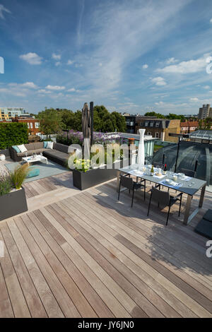 Luxurious roof terrace in London with hardwood timber decking, contemporary planters with lush planting and modern outdoor furniture Stock Photo