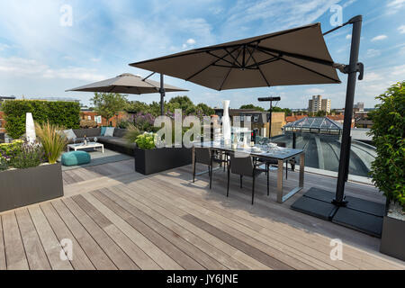 Luxurious roof terrace in London with hardwood timber decking, contemporary planters with lush planting and modern outdoor furniture Stock Photo