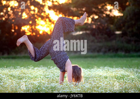 Young girl,doing handstands in a meadow of flowers. Stock Photo