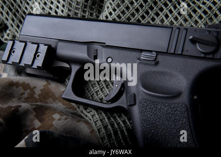 Pistal automatic short hand gun in the  US army prop background photo in lowlighting and dark shadow concept. Stock Photo