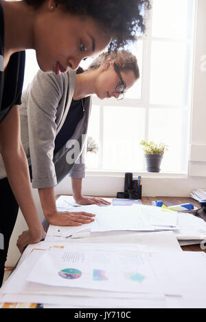 Two businesswomen studying documents in an office, vertical Stock Photo