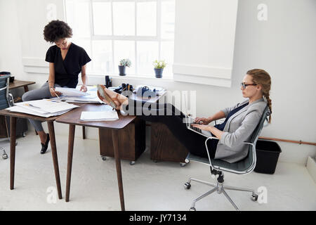Two young businesswomen work sitting casually in an office Stock Photo