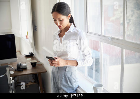 Young Asian businesswoman using smartphone in office Stock Photo