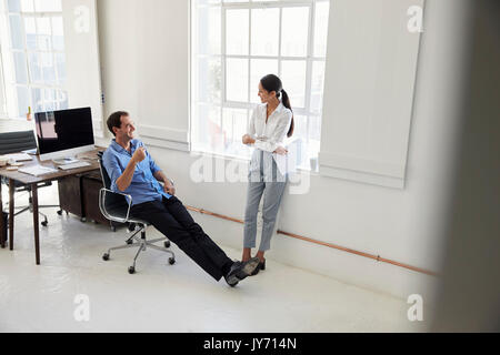 A male and a female business colleague talking in an office Stock Photo